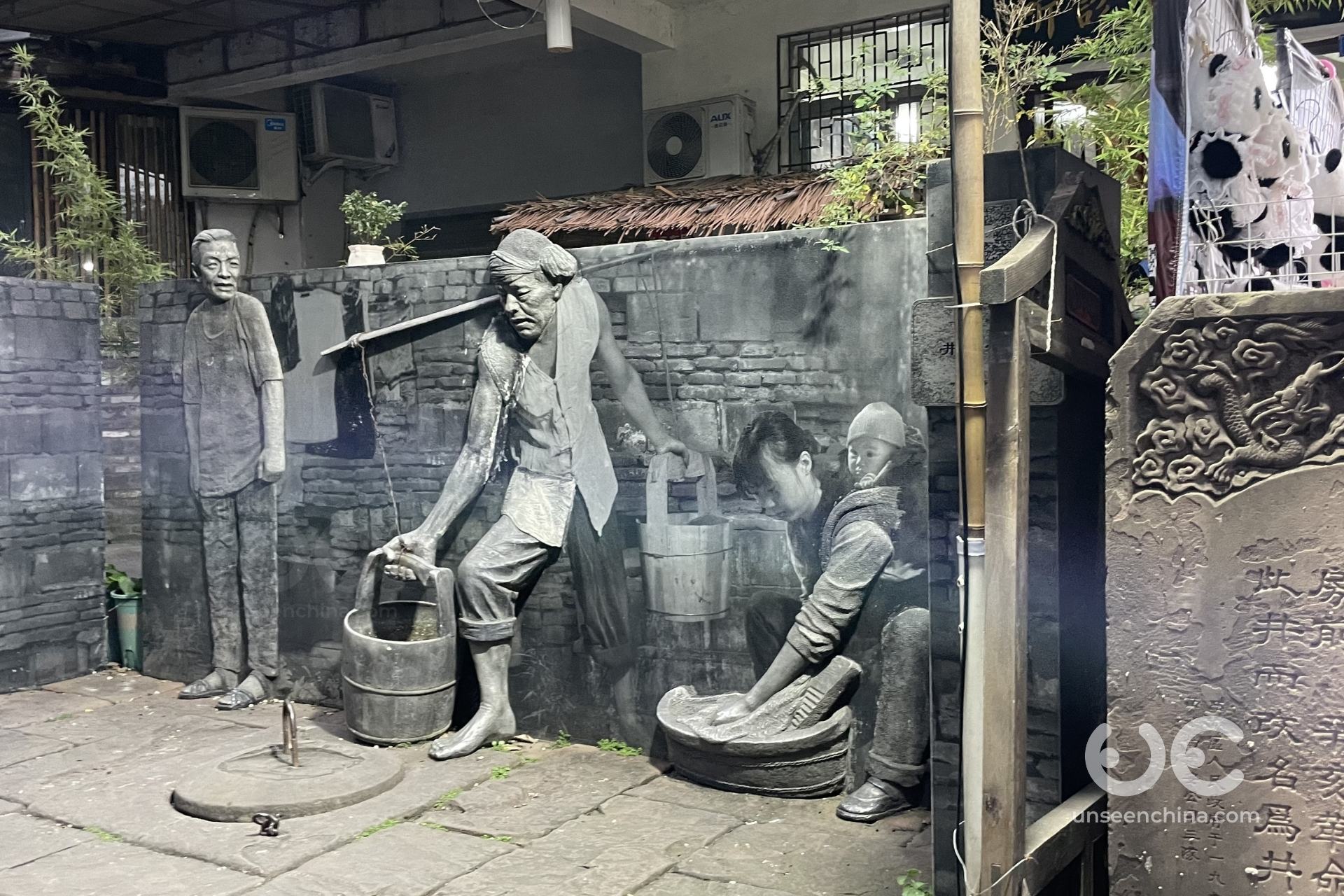 Jing Alley in Kuanzhai Alley featuring a statue illustrating traditional daily life and water washing activities.