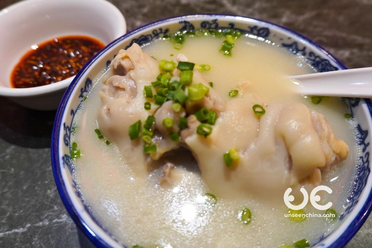 A bowl of Chengdu braised pork trotters soup with tender pork trotters and a side of chili dipping sauce